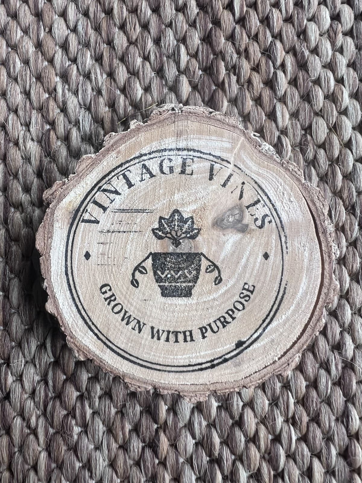 Close-up of the Vintage Vines logo stamped on a wood round